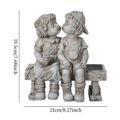 Outdoor solar powered boy and girl sitting on bench statue