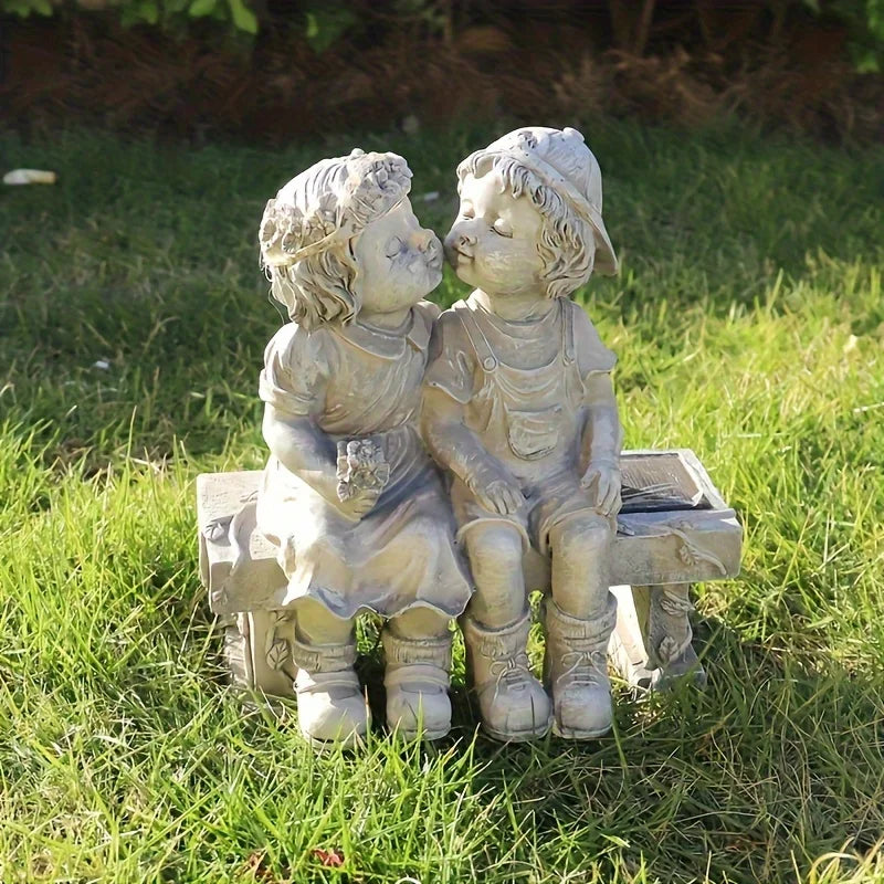 Outdoor solar powered boy and girl sitting on bench statue