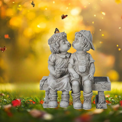 Outdoor solar powered boy and girl sitting on bench statue