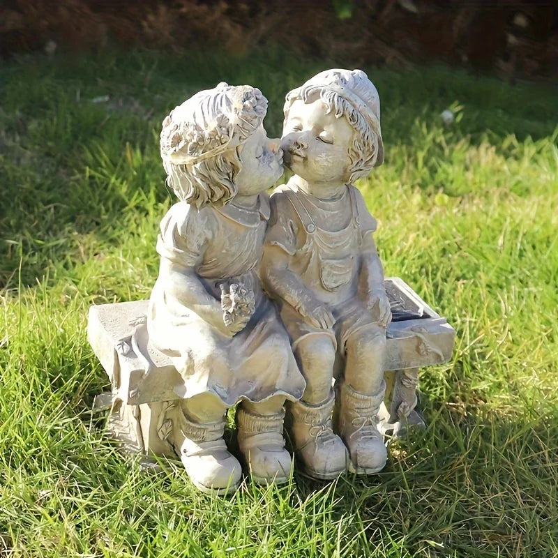 Outdoor solar powered boy and girl sitting on bench statue