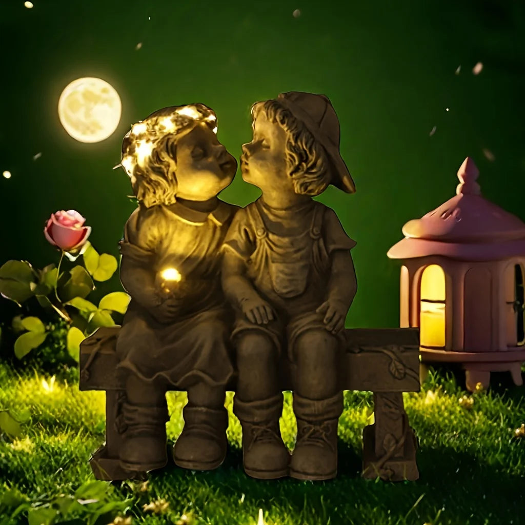 Outdoor solar powered boy and girl sitting on bench statue