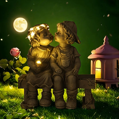 Outdoor solar powered boy and girl sitting on bench statue