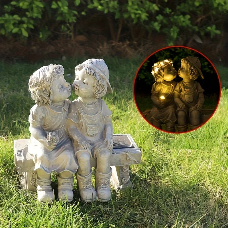 Outdoor solar powered boy and girl sitting on bench statue
