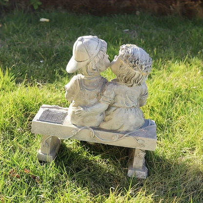 Outdoor solar powered boy and girl sitting on bench statue